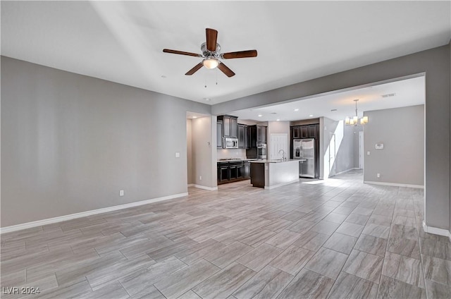 unfurnished living room with sink and ceiling fan with notable chandelier