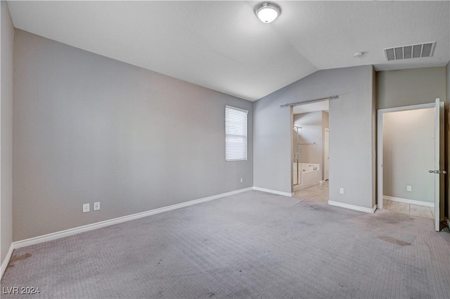 unfurnished bedroom featuring lofted ceiling and light colored carpet