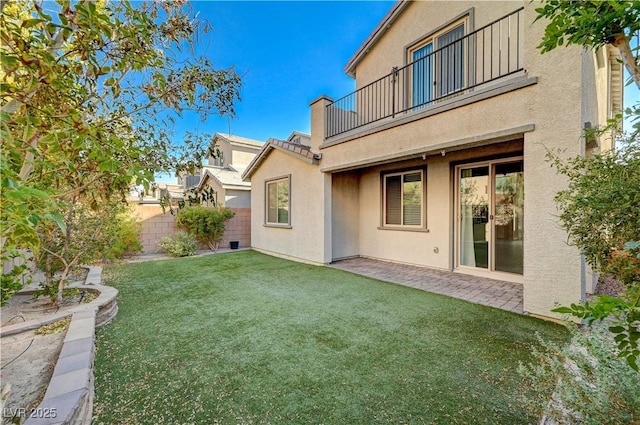 rear view of property with a yard, a patio area, and a balcony