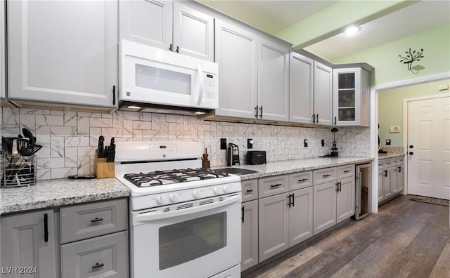 kitchen featuring gray cabinetry, white appliances, dark wood-type flooring, decorative backsplash, and light stone counters