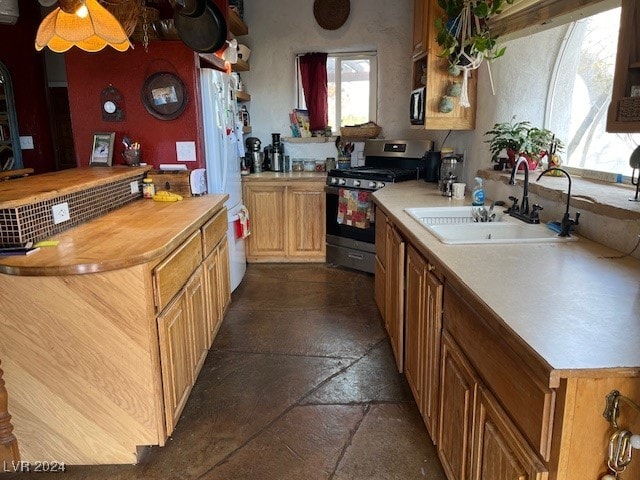 kitchen featuring gas range, ceiling fan, and sink