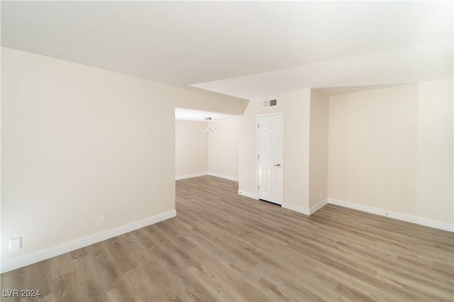 unfurnished room featuring an inviting chandelier and light wood-type flooring