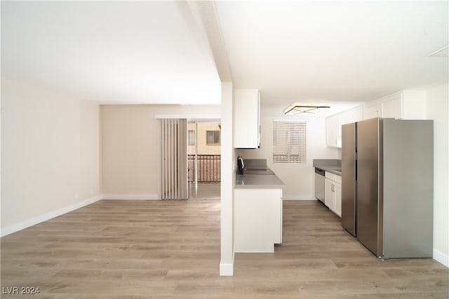 kitchen with white cabinets, appliances with stainless steel finishes, and light hardwood / wood-style flooring