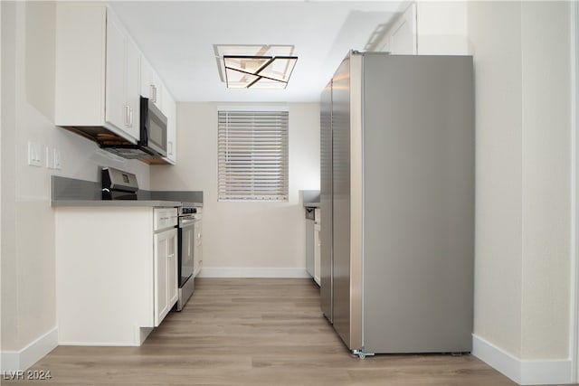 kitchen featuring stainless steel appliances, white cabinetry, and light hardwood / wood-style flooring