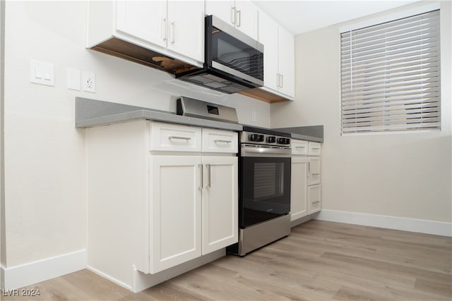 kitchen with appliances with stainless steel finishes, light wood-type flooring, and white cabinetry