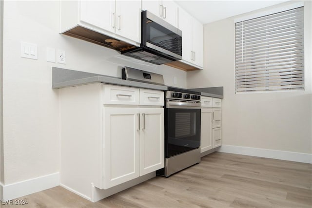 5260 River Glen Dr Unit 261, Las Vegas, NV 89103 - kitchen featuring appliances with stainless steel finishes, light wood finished floors, white cabinets, and dark countertops