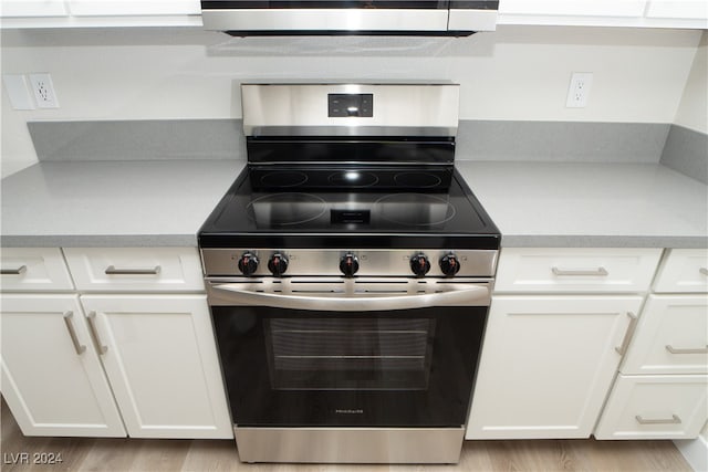 kitchen with stainless steel range, light wood-type flooring, and white cabinets