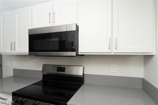 kitchen featuring white cabinets and black range