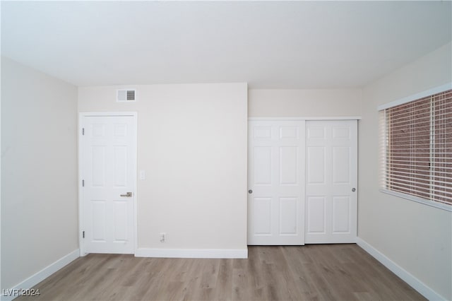 unfurnished bedroom with light hardwood / wood-style floors and a closet