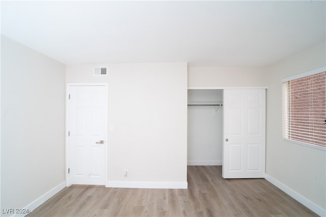 unfurnished bedroom featuring light hardwood / wood-style floors and a closet