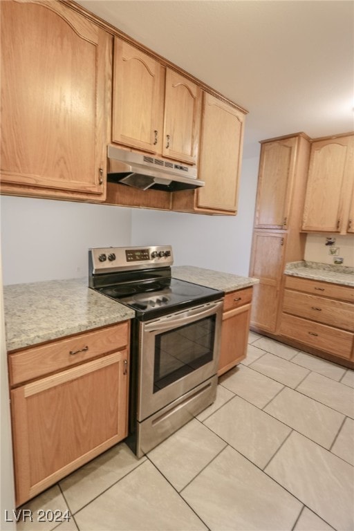 kitchen with light brown cabinets, light tile patterned flooring, and stainless steel electric range