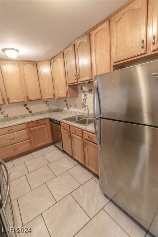 kitchen featuring sink, light stone counters, light brown cabinetry, light tile patterned floors, and appliances with stainless steel finishes