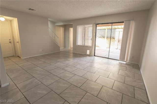 tiled spare room featuring a textured ceiling