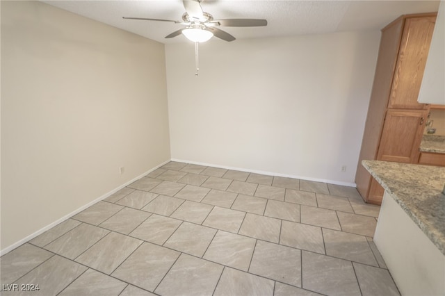 tiled spare room with ceiling fan and a textured ceiling