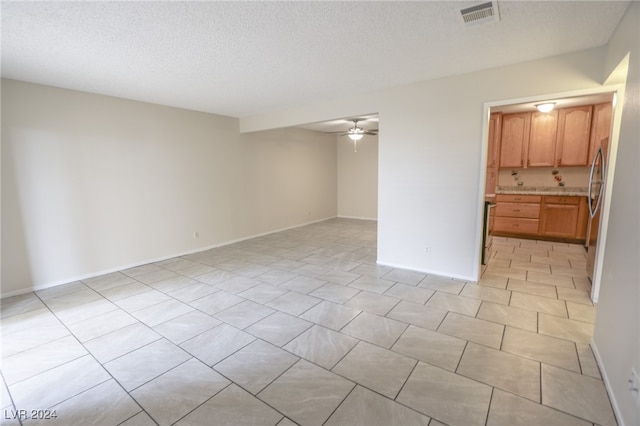 empty room with ceiling fan and a textured ceiling