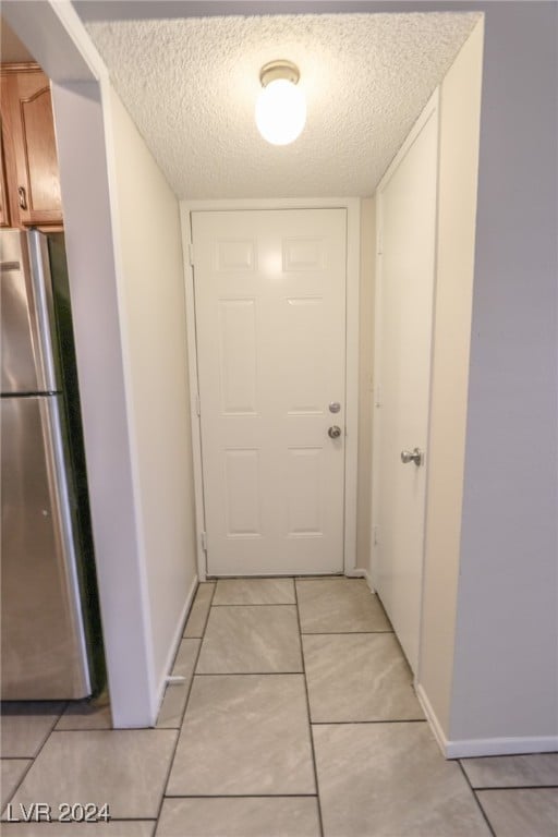 hallway with light tile patterned floors and a textured ceiling