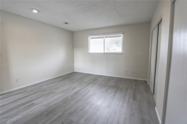 unfurnished bedroom featuring a textured ceiling and light hardwood / wood-style flooring