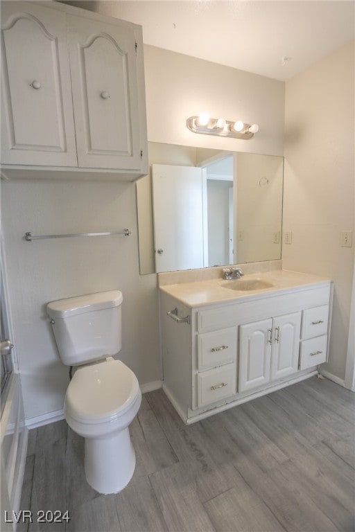 full bathroom featuring shower / bath combination with glass door, hardwood / wood-style floors, vanity, and toilet