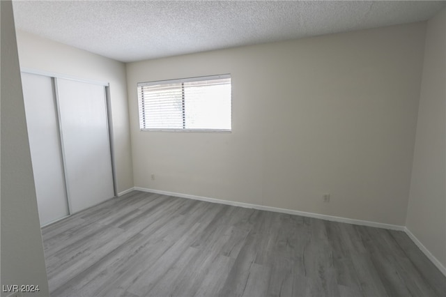 unfurnished bedroom with hardwood / wood-style floors, a textured ceiling, and a closet