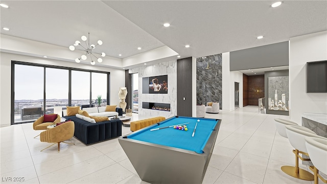 playroom featuring a high end fireplace, pool table, a tray ceiling, a chandelier, and recessed lighting