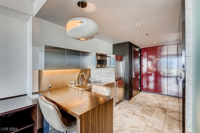 kitchen featuring kitchen peninsula, a breakfast bar, and sink