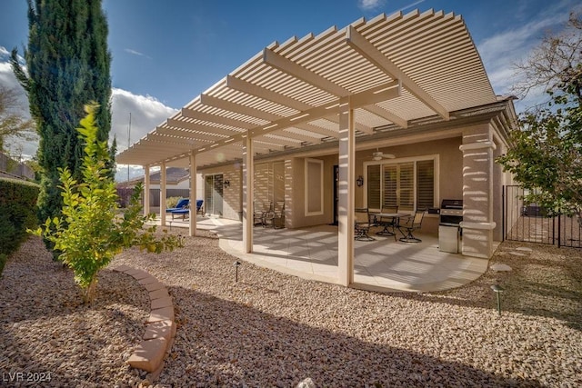 rear view of property with ceiling fan, a patio area, and a pergola