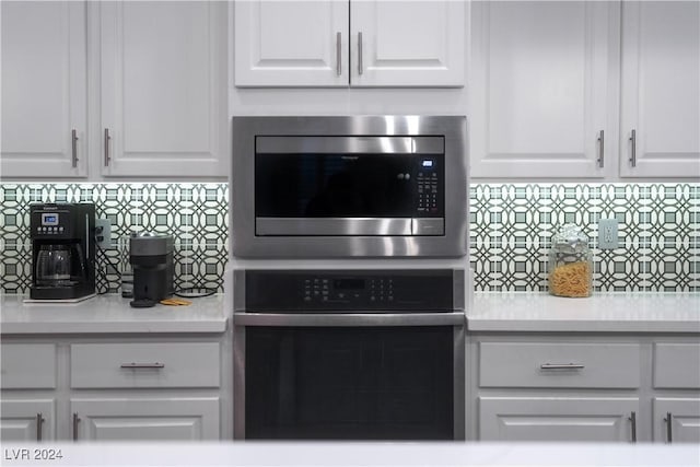 kitchen with backsplash, white cabinetry, and stainless steel appliances