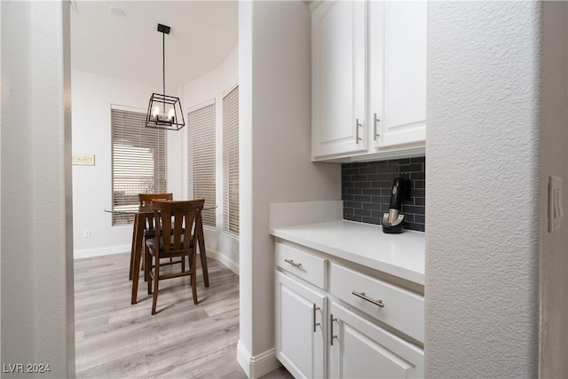 kitchen featuring tasteful backsplash, decorative light fixtures, a chandelier, white cabinets, and light hardwood / wood-style floors