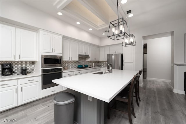 kitchen with white cabinets, sink, stainless steel appliances, and a center island with sink