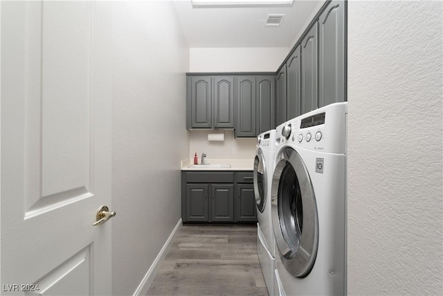 washroom with dark hardwood / wood-style flooring, washer and clothes dryer, cabinets, and sink