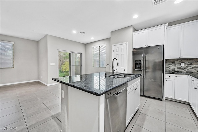 kitchen featuring stainless steel appliances, sink, a center island with sink, dark stone countertops, and white cabinets