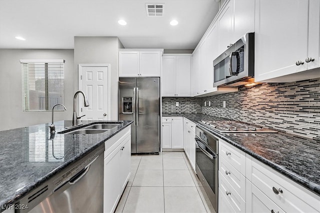 kitchen featuring white cabinets, appliances with stainless steel finishes, dark stone counters, and sink