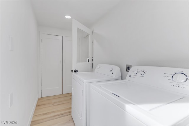 clothes washing area featuring light hardwood / wood-style floors and washer and clothes dryer