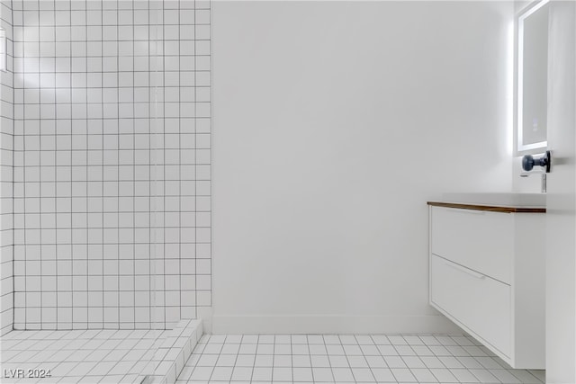 bathroom with tile patterned flooring, vanity, and tiled shower