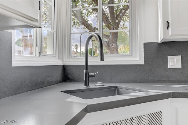 interior details featuring white cabinets, sink, and tasteful backsplash