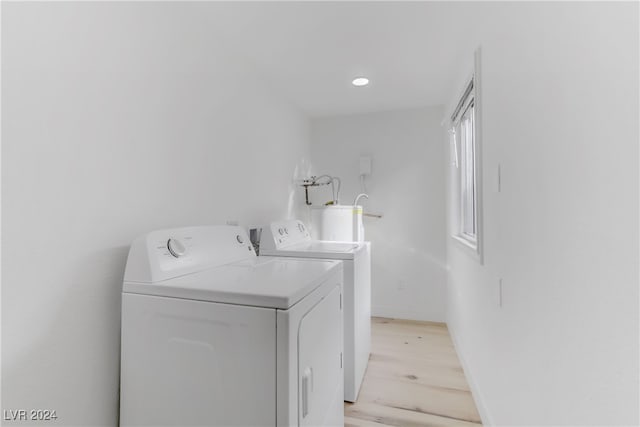 laundry area featuring water heater, light wood-type flooring, and washing machine and clothes dryer