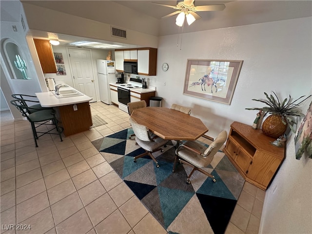 tiled dining room with ceiling fan and sink