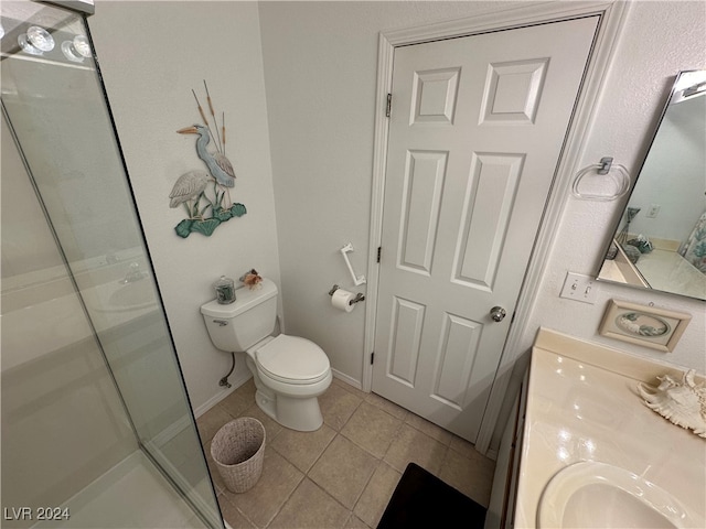 bathroom featuring tile patterned flooring, vanity, toilet, and a shower with shower door