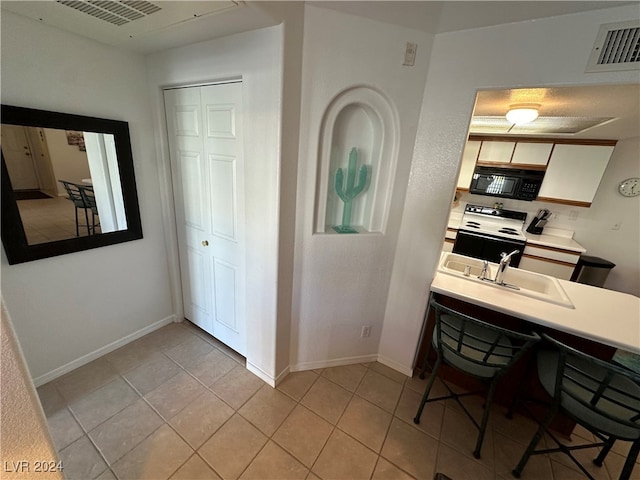 kitchen featuring sink, light tile patterned floors, and white electric range