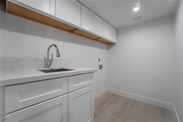 laundry area with sink, cabinets, light wood-type flooring, electric dryer hookup, and washer hookup