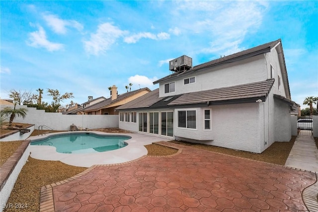 rear view of property featuring a fenced in pool, a patio, and central air condition unit