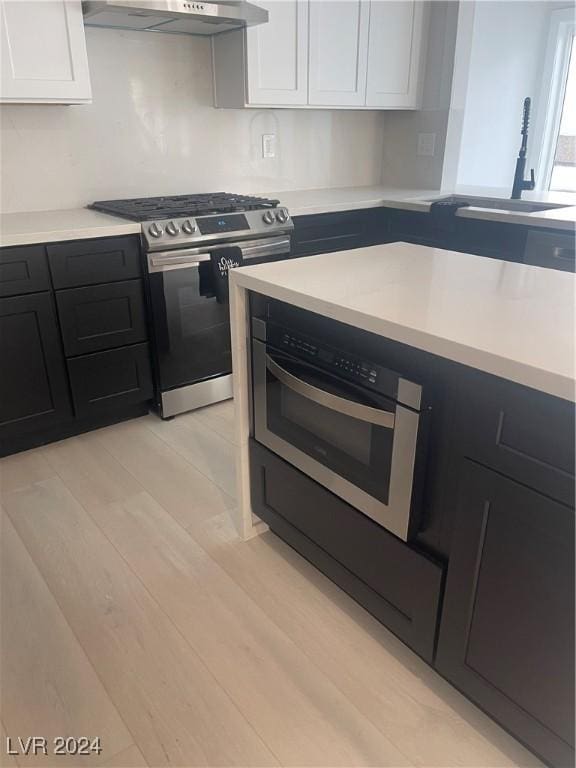 kitchen featuring white cabinetry, gas range, sink, and light wood-type flooring