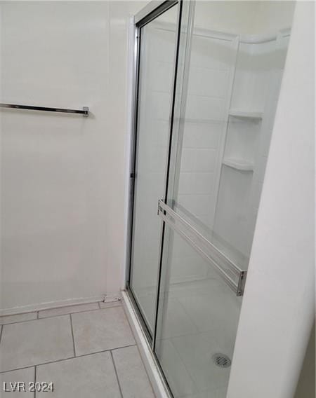 bathroom with tile patterned floors and a shower with door