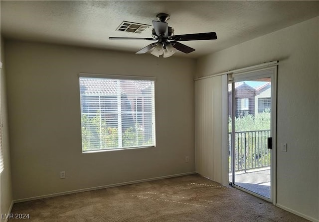 carpeted empty room featuring a textured ceiling, ceiling fan, and a healthy amount of sunlight