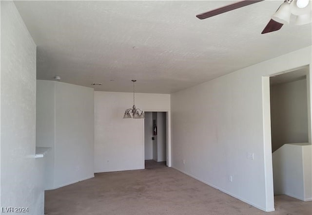 carpeted spare room with a textured ceiling and ceiling fan with notable chandelier