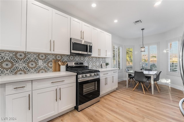 kitchen featuring backsplash, stainless steel appliances, decorative light fixtures, light hardwood / wood-style flooring, and white cabinetry