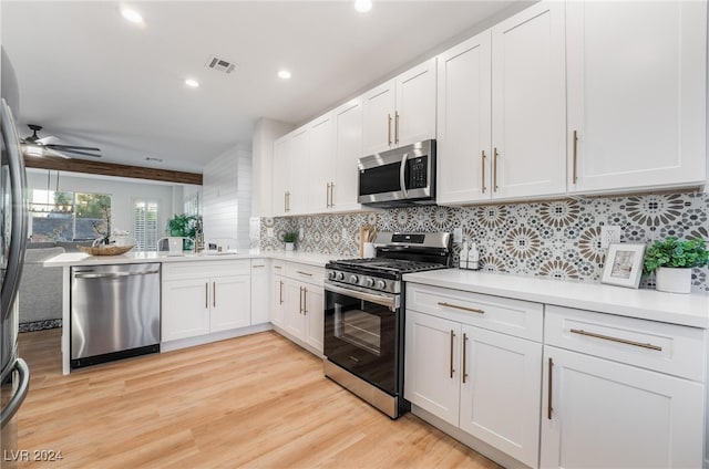 kitchen with light hardwood / wood-style flooring, decorative backsplash, ceiling fan, appliances with stainless steel finishes, and white cabinetry