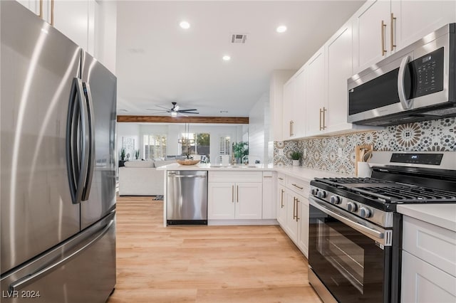 kitchen with ceiling fan, stainless steel appliances, decorative backsplash, white cabinets, and light wood-type flooring