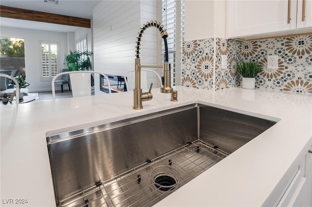 details with tasteful backsplash, sink, and white cabinets