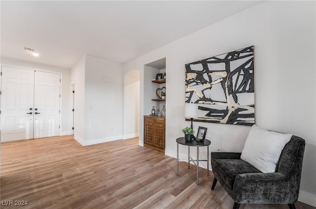 sitting room with built in shelves and light hardwood / wood-style flooring